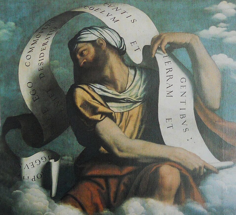 A painting of a young (or middle-aged) bearded man in a yellow tunic with a white headdress, sitting on a cloud. A large white scroll unfurls out of his hands, bearing a Latin verse from the Book of Haggai.