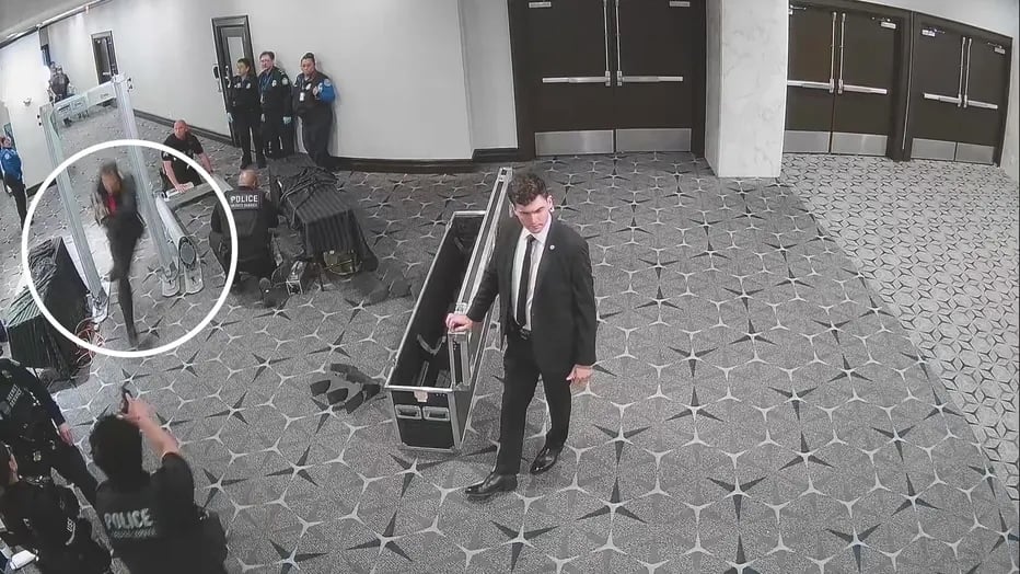 Un hombre corre a través de un detector de metales mientras varios agentes de policía y del Servicio Secreto observan. Otro agente está agachado y parece estar apuntando con un arma al hombre que corre. 