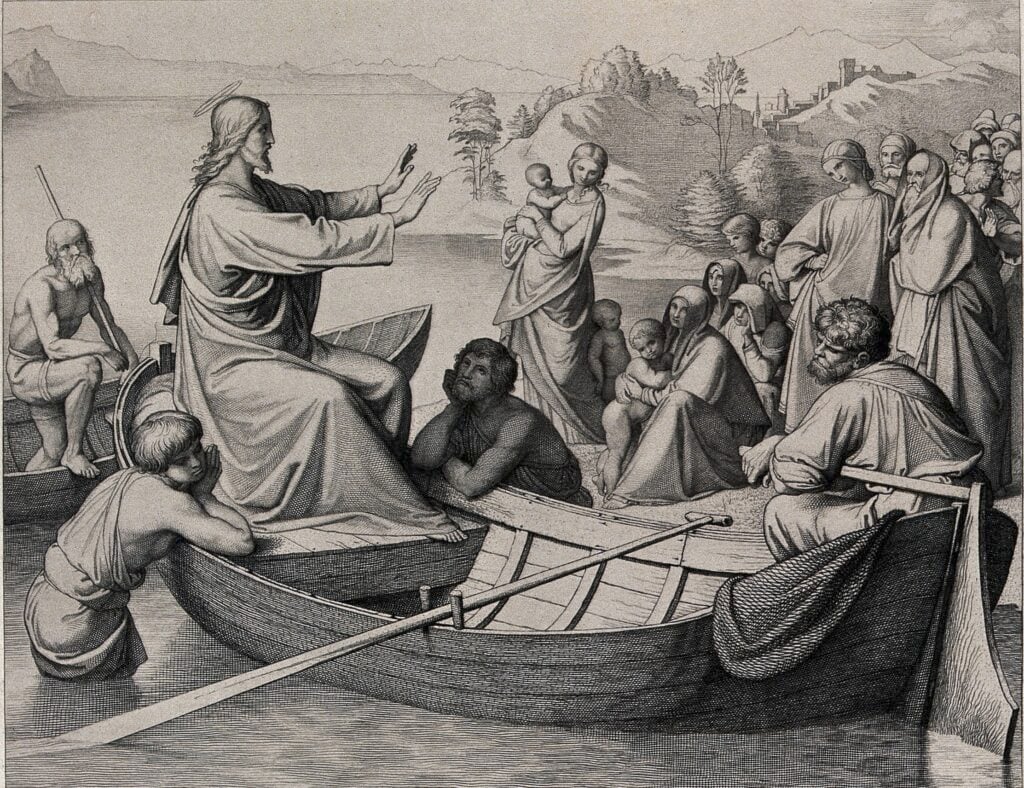 An etching of Jesus, sitting in a boat that has bben brought up to the shore. He holds his hands out to address a crowd that's gathered to hear him speak. Some apostles are listening intently, leaning against the boat to hold it steady. In the far backgroun, you can see a few tall buildings just beyond some hills.